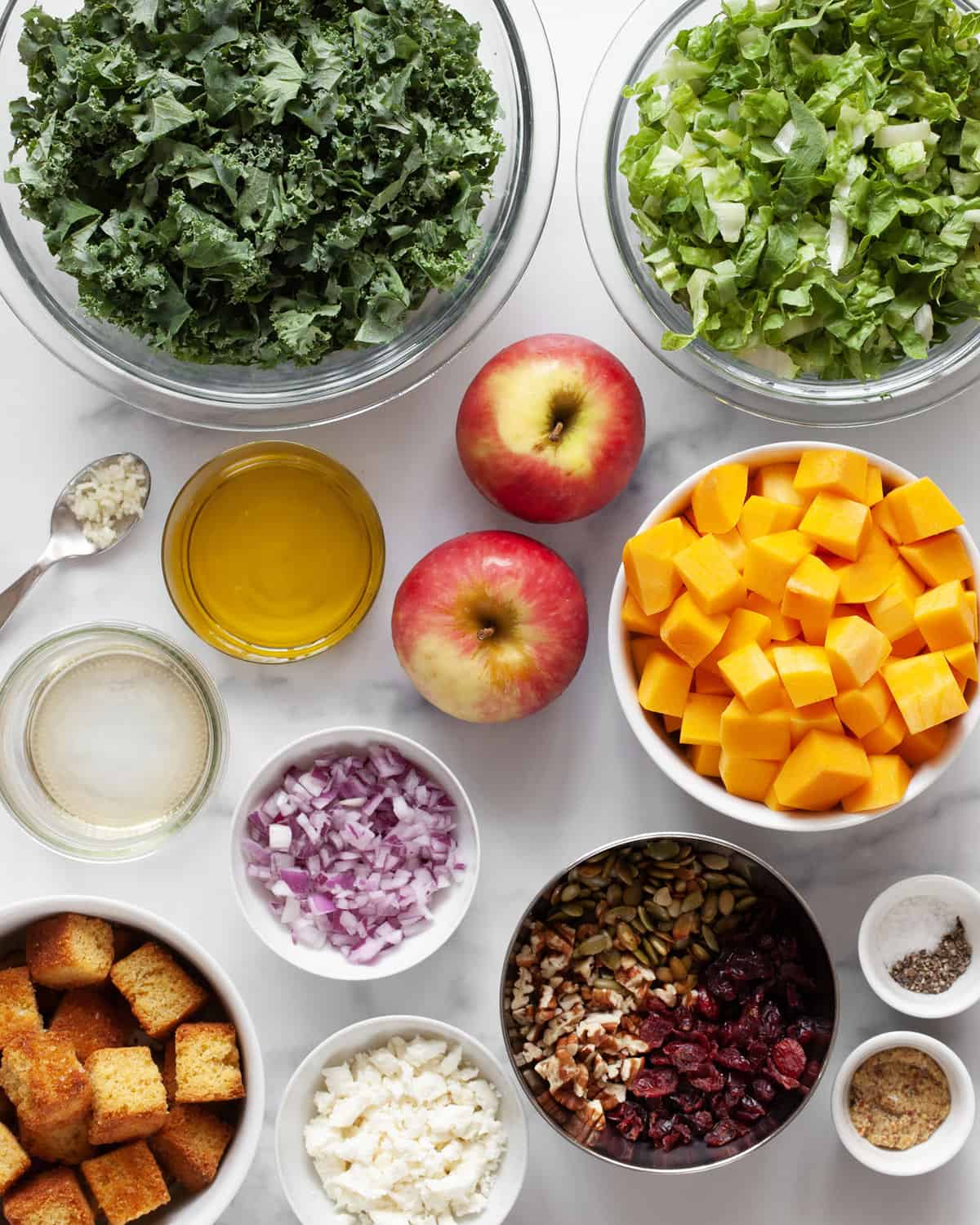 Ingredients including kale, romaine, butternut squash, apples, pecans, goat cheese, apple cider vinegar and olive oil.
