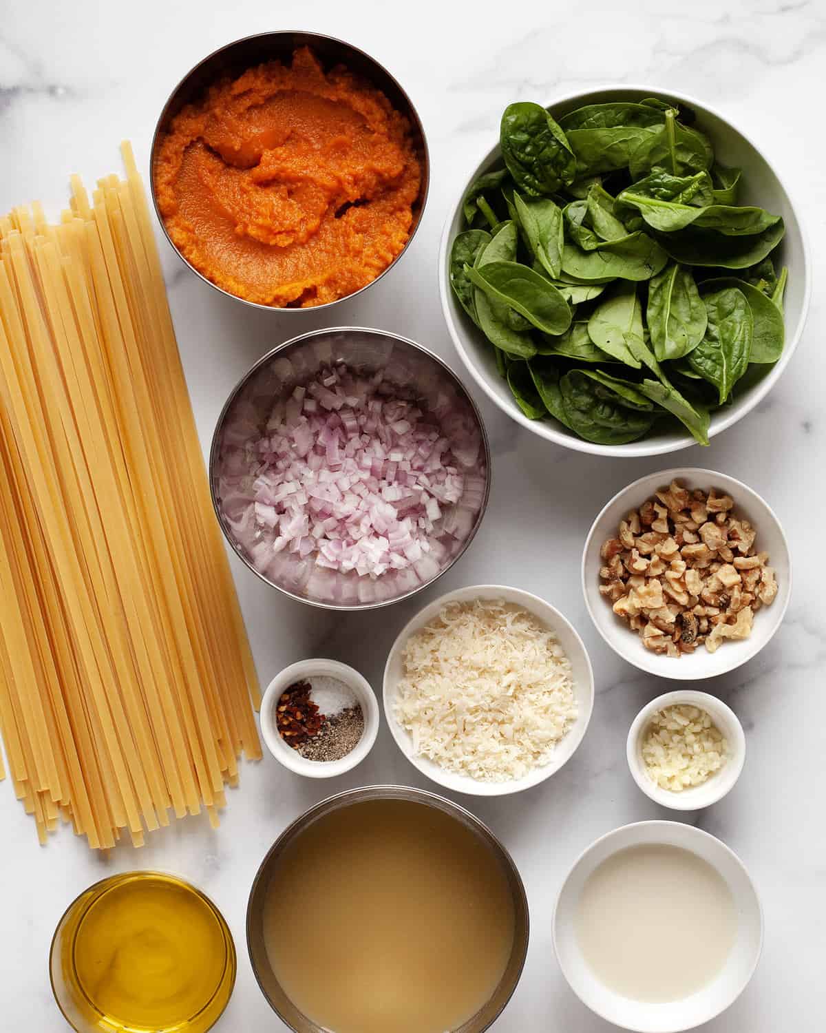 Ingredients including pumpkin puree, pasta, spinach, walnuts, parmensa, milk, vegetable broth, shallots, spices and garlic.