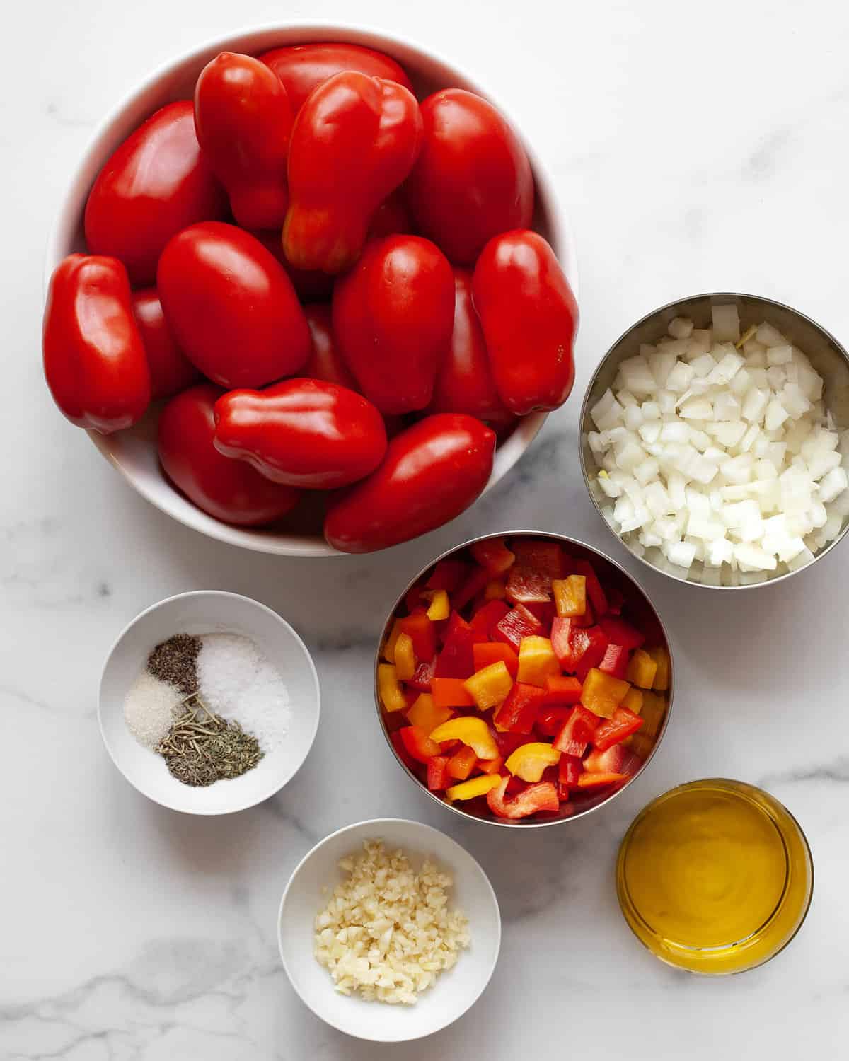 Ingredients including tomatoes, onions, olive oil, garlic, spices and bell peppers.