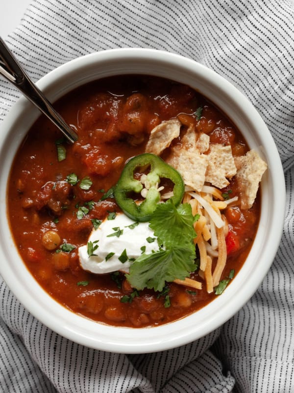 Chili topped with tortilla chips, cilantro, jalapeño and sour cream in a bowl.