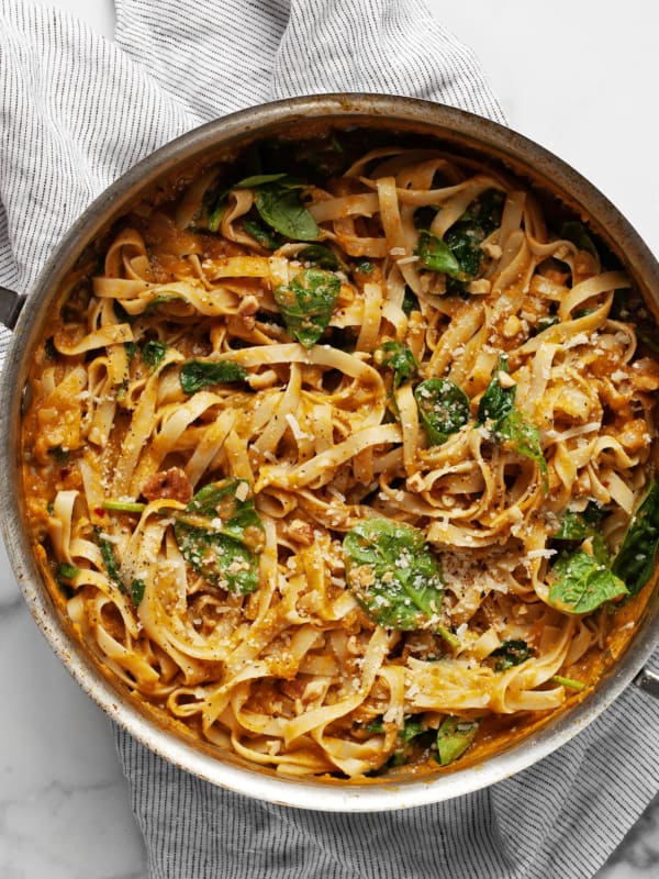 Pasta with pumpkin sauce, spinach and parmesan in a pan.