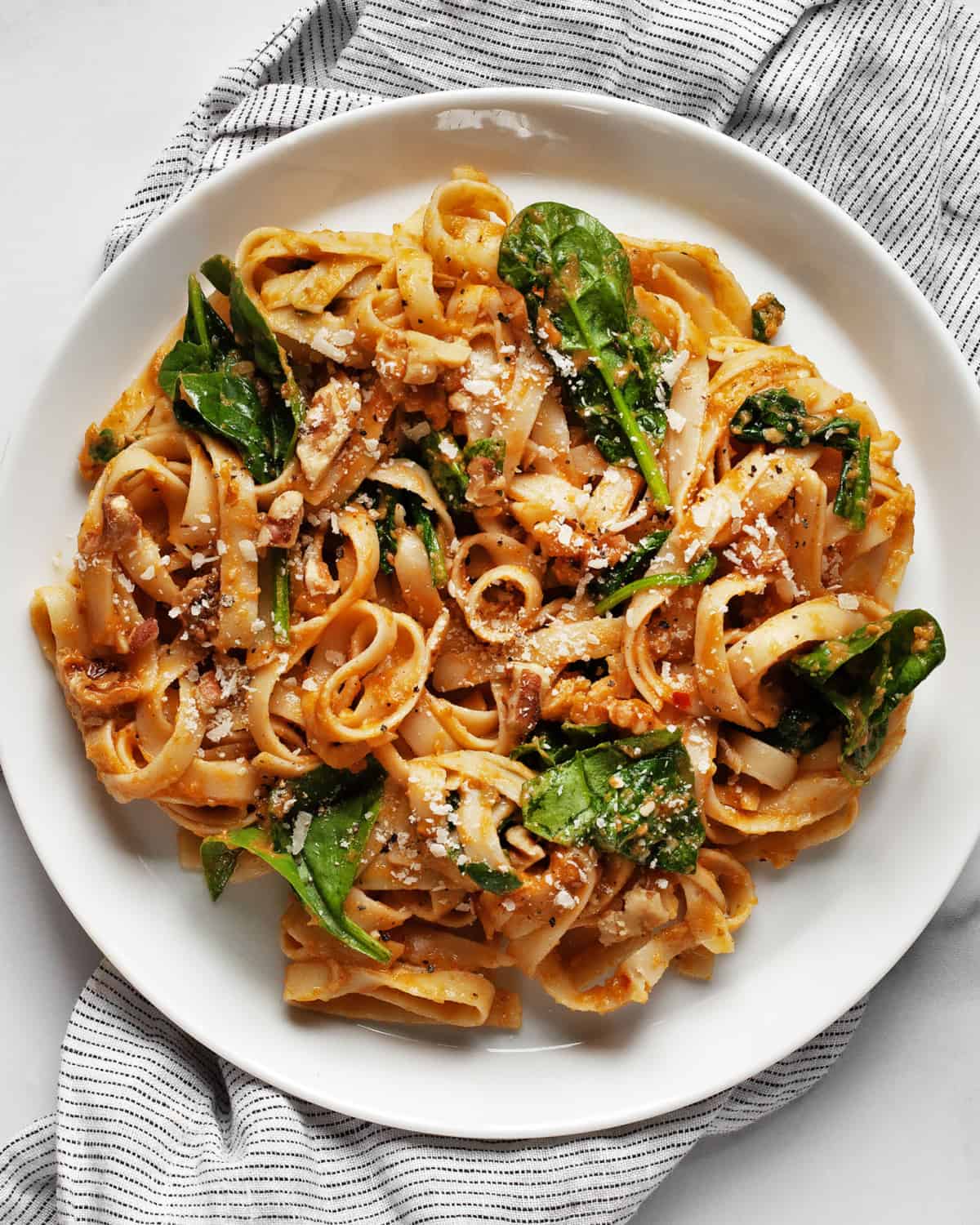 Pumpkin pasta with spinach, parmesan and walnuts on a plate.