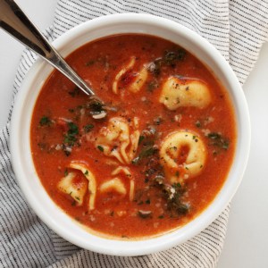 One bowl of creamy tomato soup with tortellini and kale.