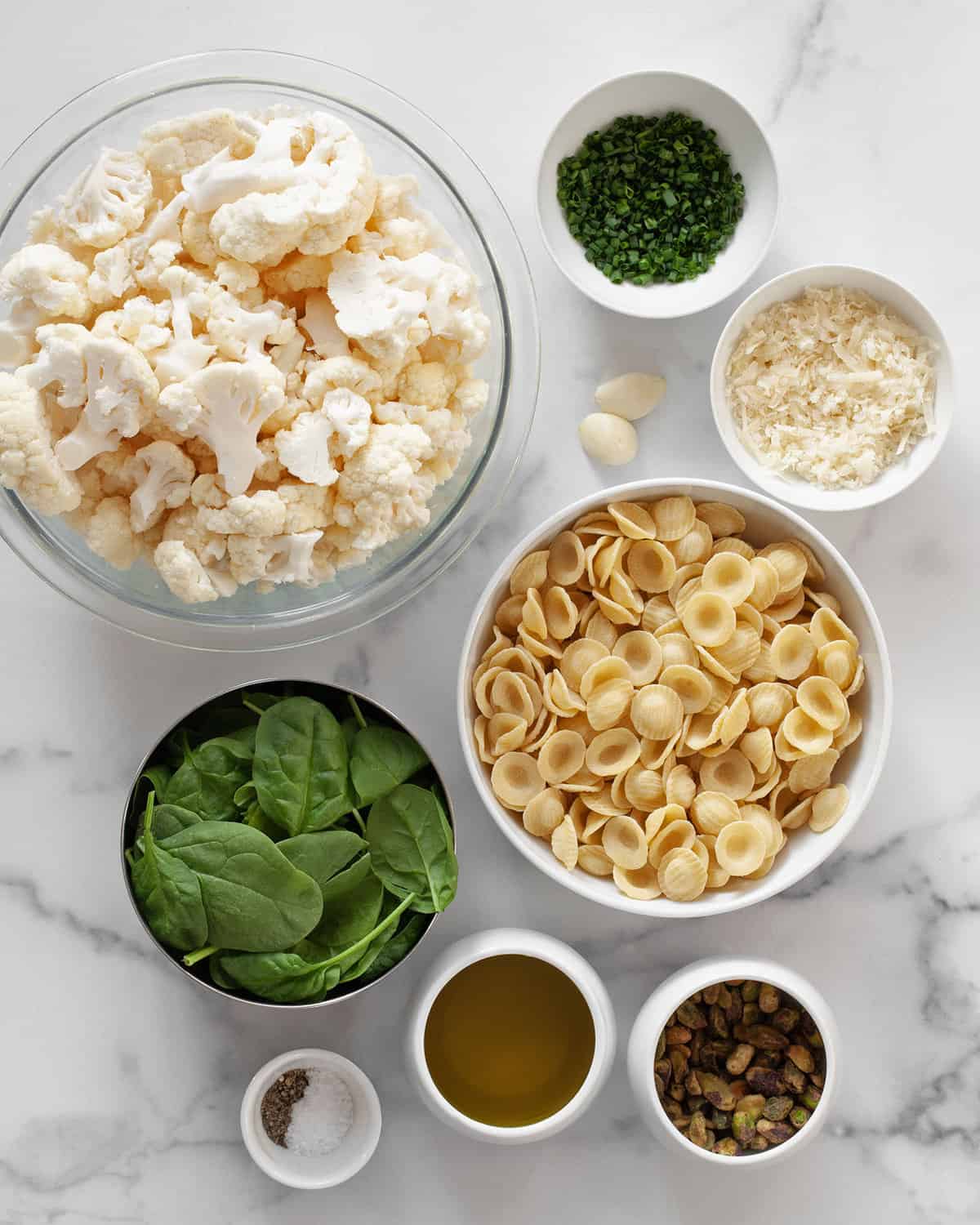 Ingredients including cauliflower, spinach, parmesan, pistachios, olive oil, garlic, chives, salt and pepper.