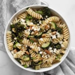Rasoted broccolini and zucchini pasta salad with walnuts and feta on a plate.