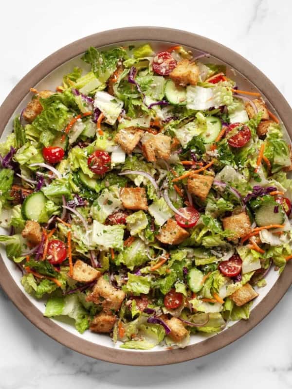 Salad tossed with vinaigrette in a big bowl.