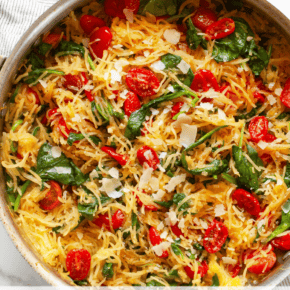 Roasted spaghetti squash with tomatoes and spinach in a skillet.