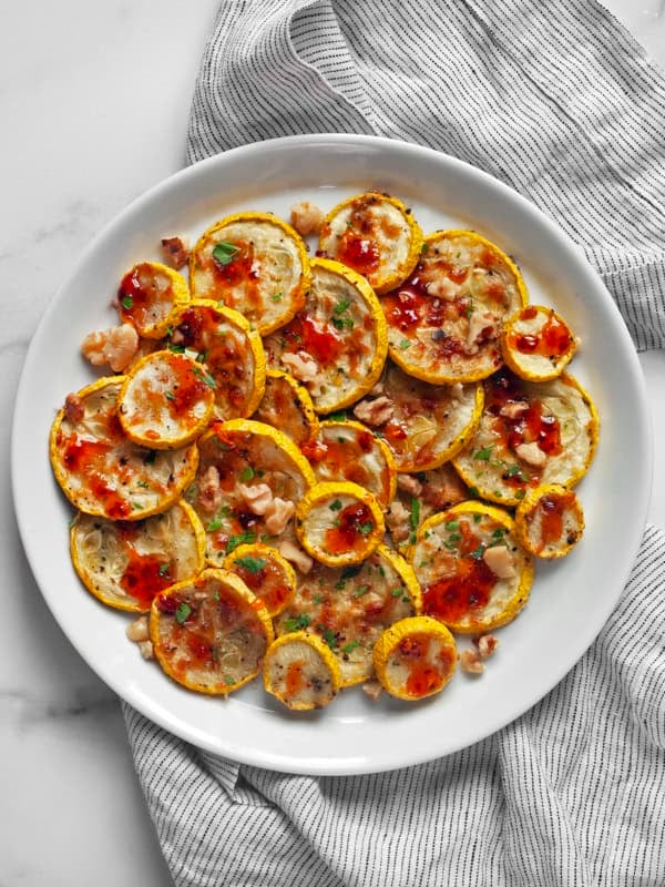 Parmesan roasted yellow squash drizzled with hot honey on a plate.