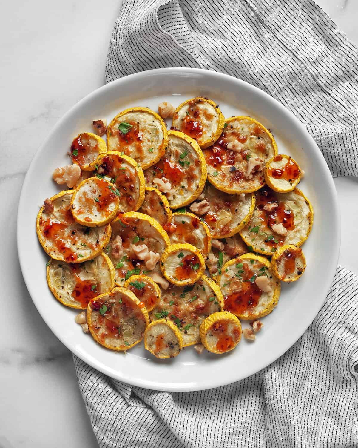 Parmesan roasted yellow squash drizzled with hot honey on a plate.