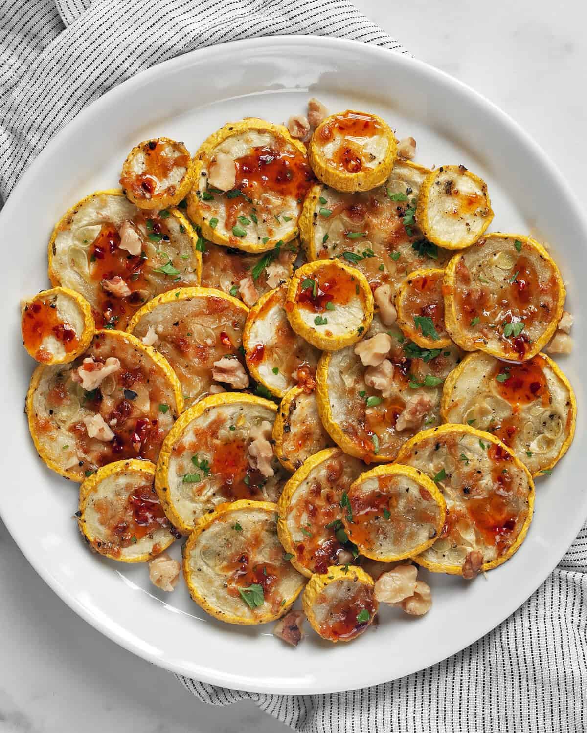 Parmesan roasted yellow squash drizzled with hot honey on a plate.