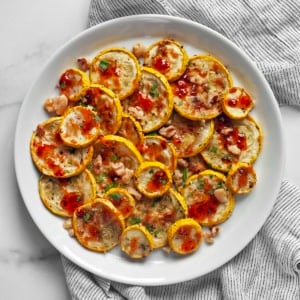 Parmesan roasted yellow squash drizzled with hot honey on a plate.