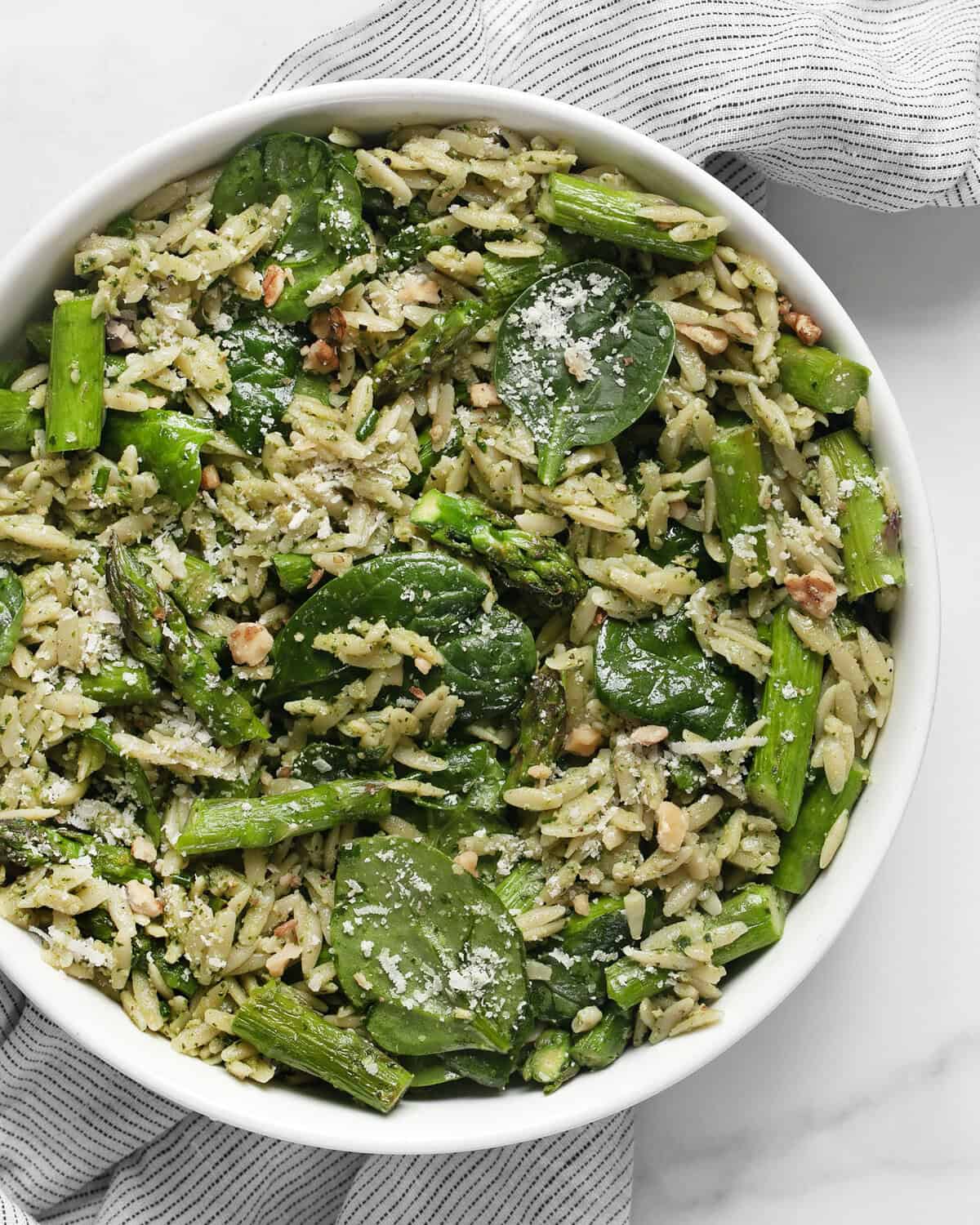 Spinach pesto orzo with roasted asparagus in a bowl.
