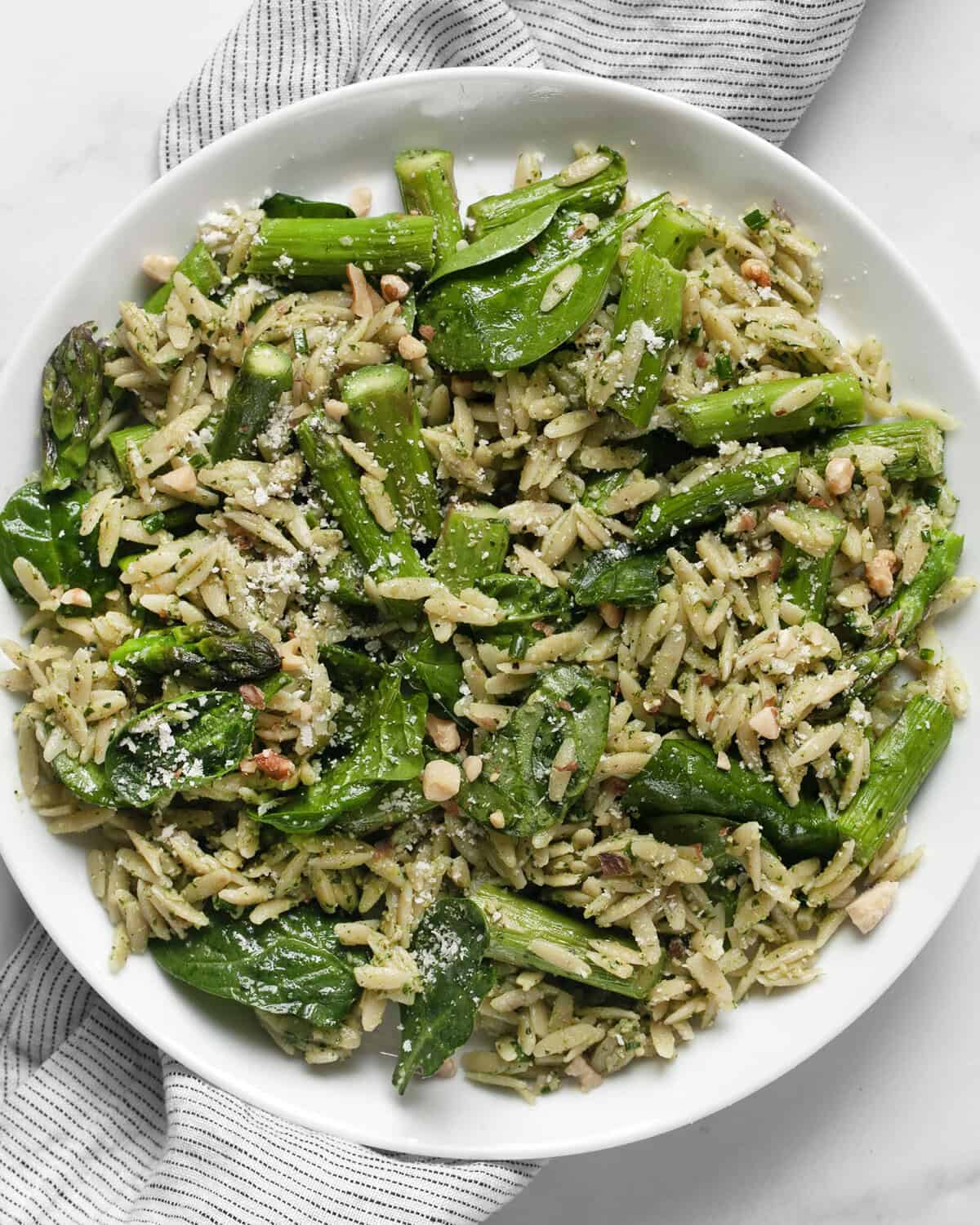 Spinach pesto orzo with roasted asparagus on a plate.