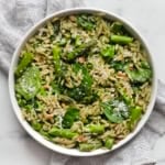 Spinach pesto orzo with roasted asparagus in a bowl.