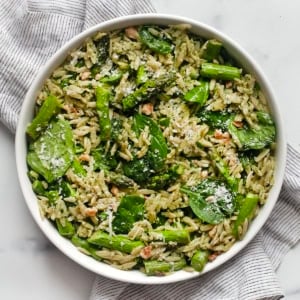 Spinach pesto orzo with roasted asparagus in a bowl.