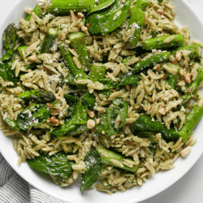 Spinach pesto orzo with roasted asparagus on a plate.