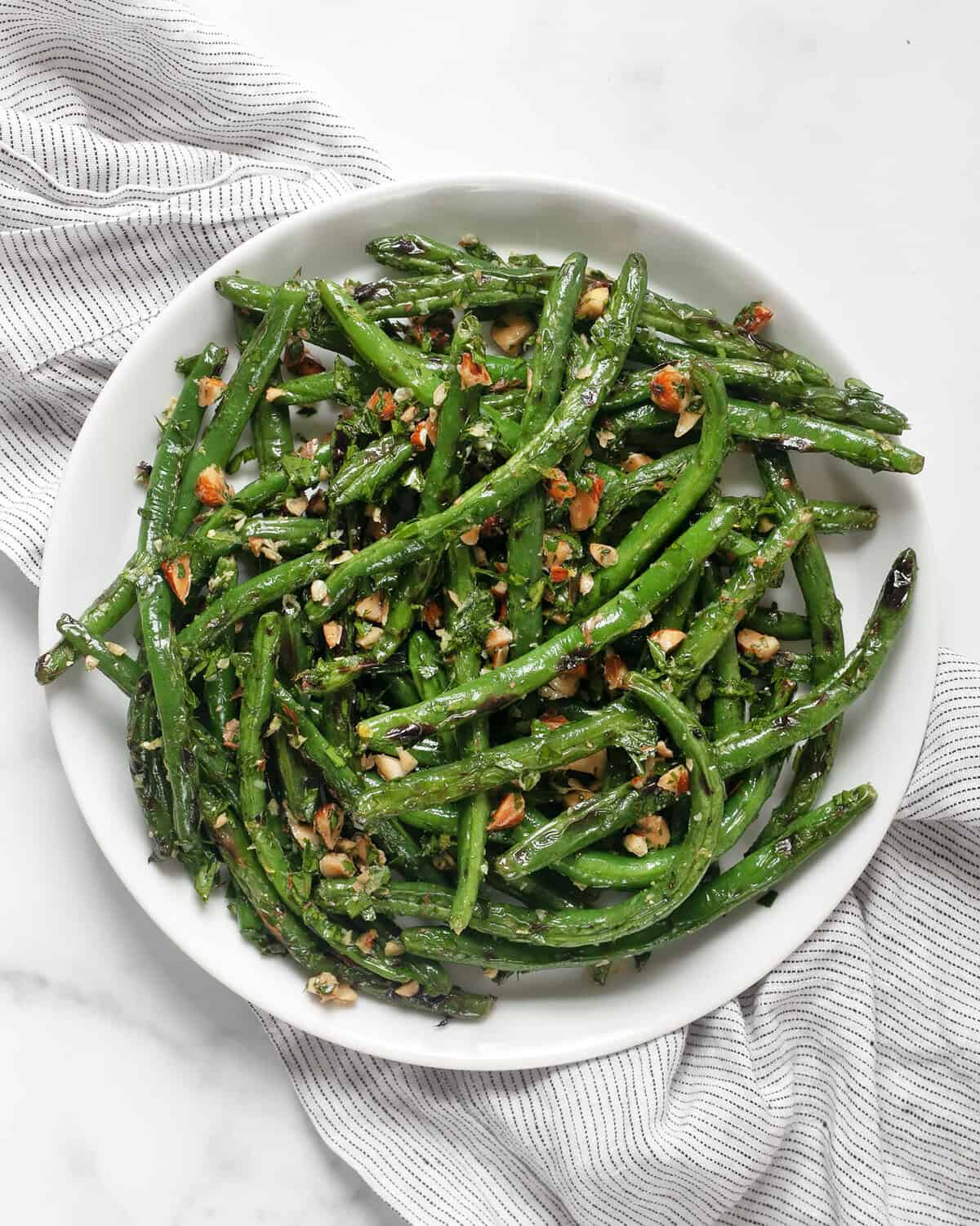 Grilled green beans with almond gremolata on a plate.