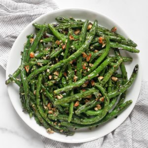 Grilled green beans with almond gremolata on a plate.