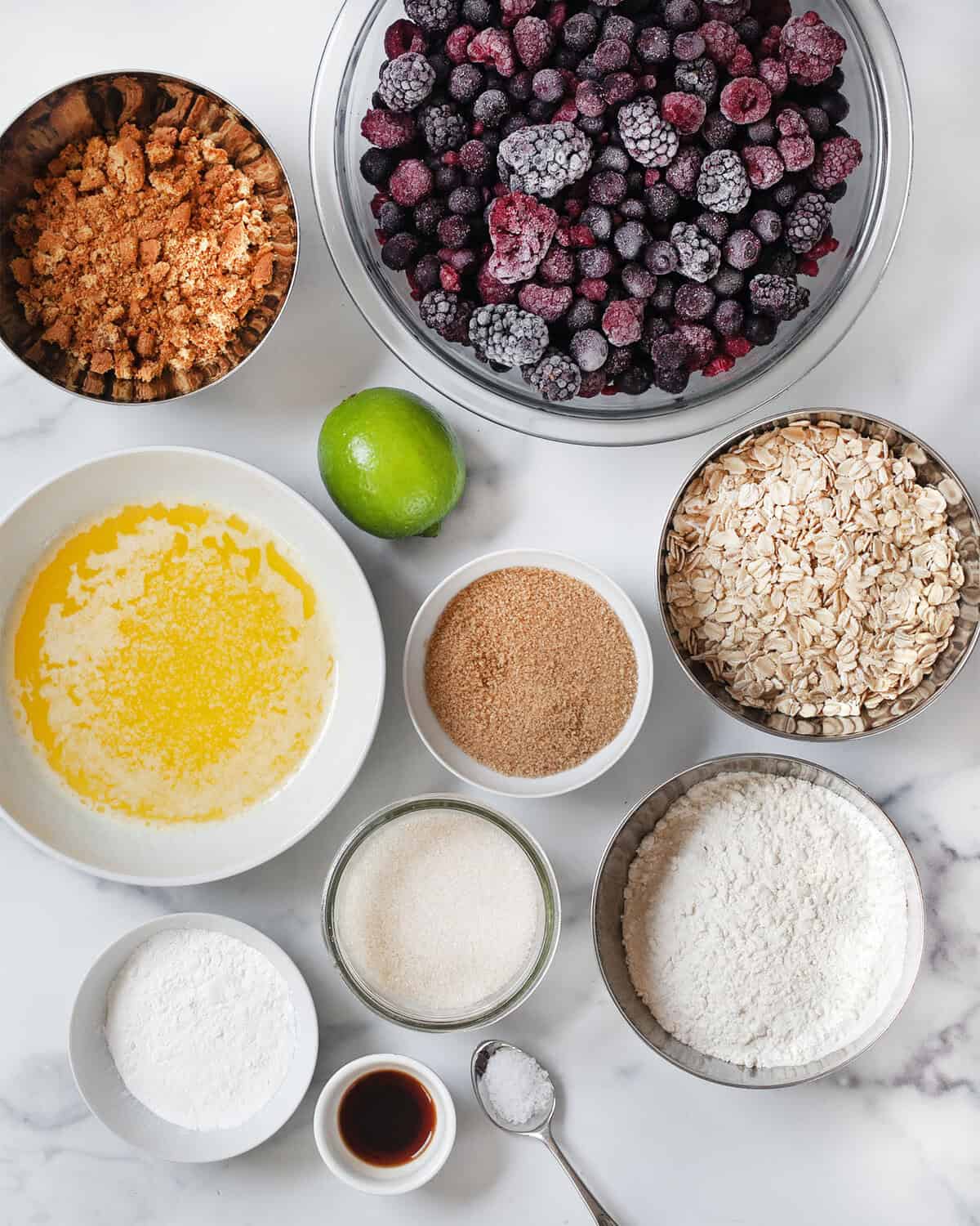 Ingredients including blueberries, raspberries, blackberries, lime, oats, gingersnaps, melted butter, flour, brown sugar, granulated sugar and vanilla extract.