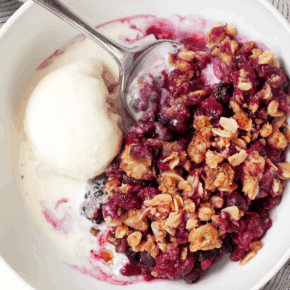 Mixed berry crumble in a serving bowl with a scoop of ice cream.
