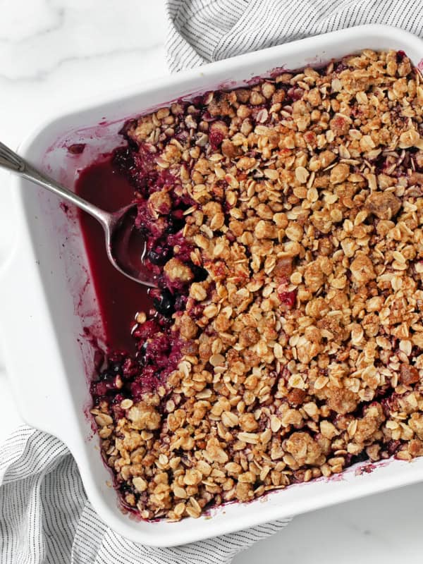 Mixed berry crumble in a dish with a spoon.