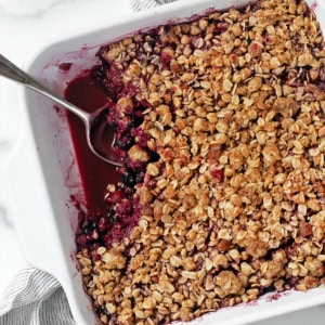 Mixed berry crumble in a dish with a spoon.