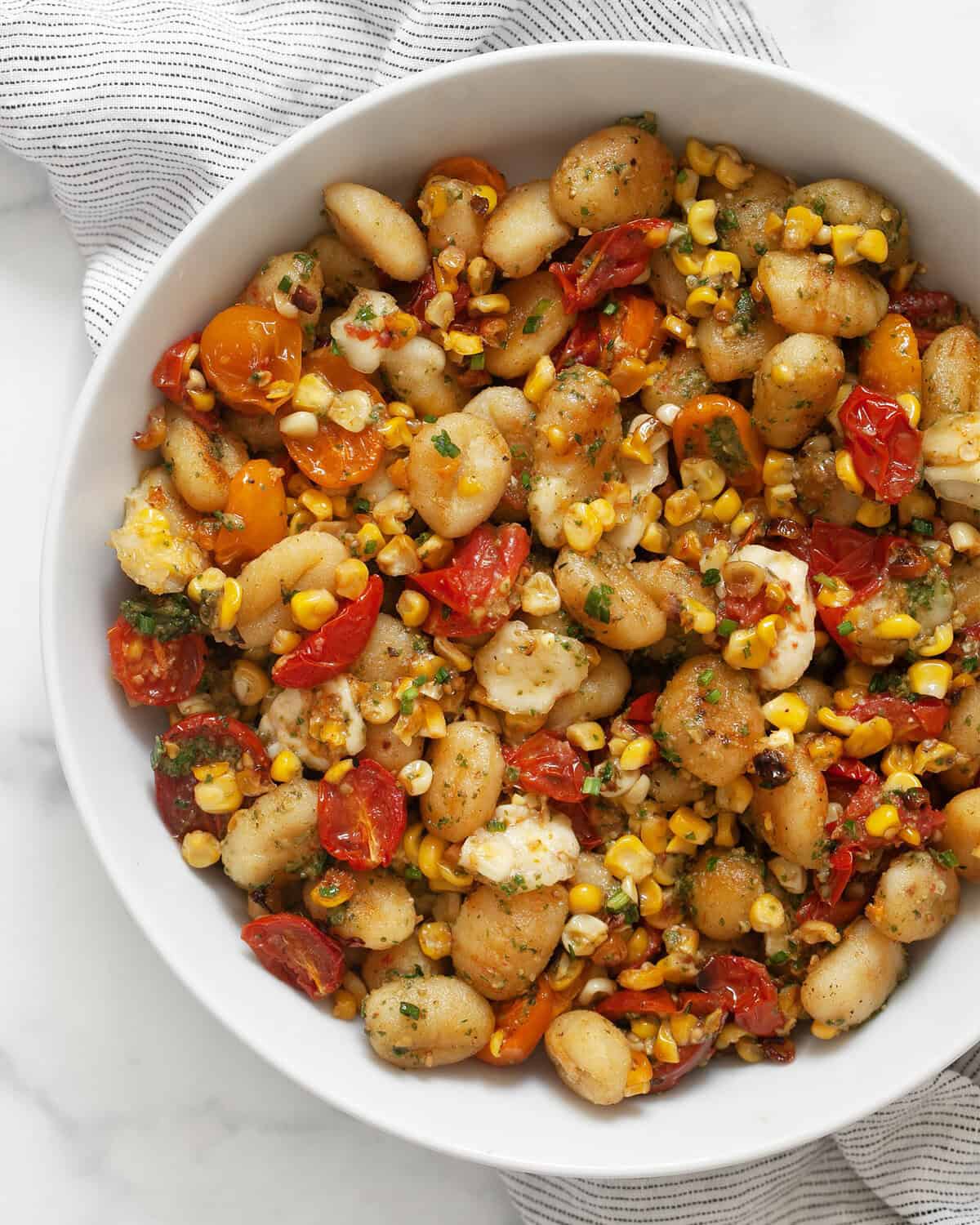 Sheet pan gnocchi with tomatoes and corn in a bowl.