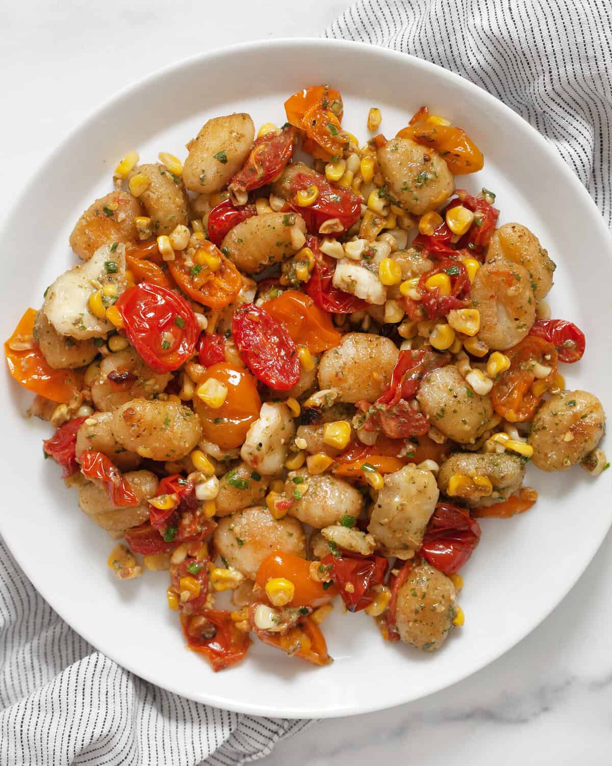 Sheet pan gnocchi with tomatoes and corn on a plate.