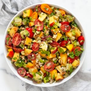 Chopped salad with peaches and tomatoes in a bowl.