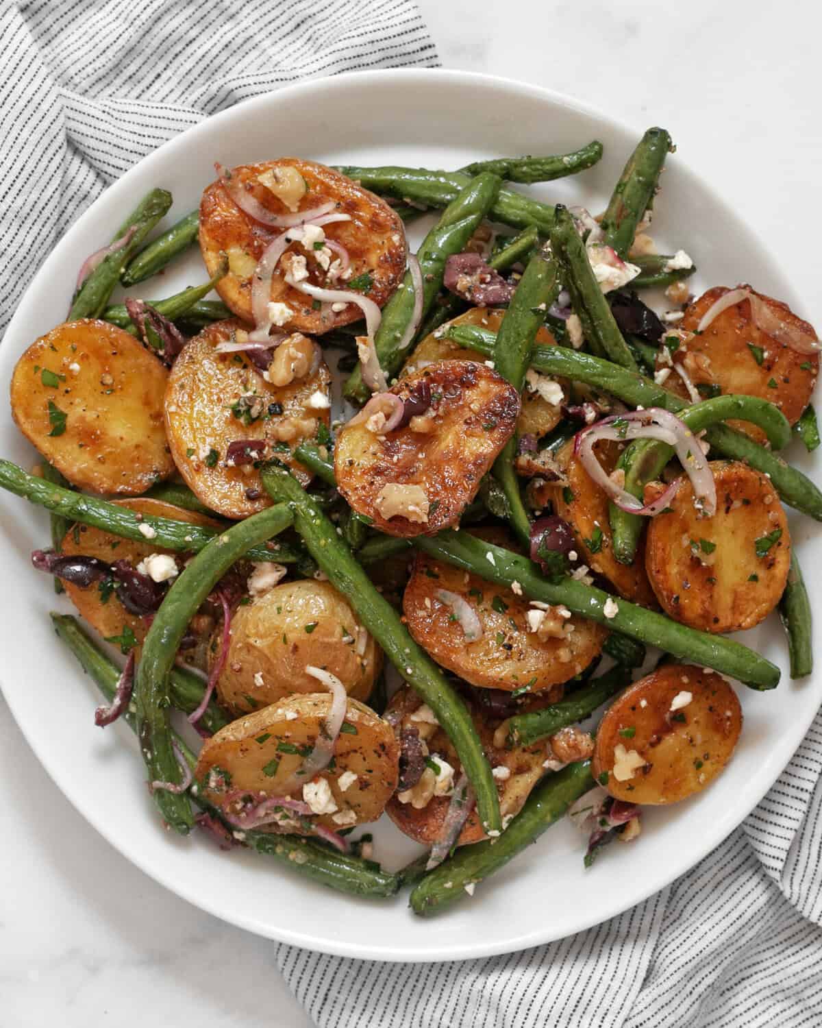 Roasted potato and green bean salad on a plate.
