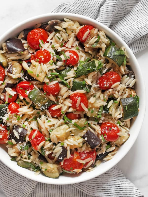 Roasted eggplant, zucchini and tomato orzo in a bowl.