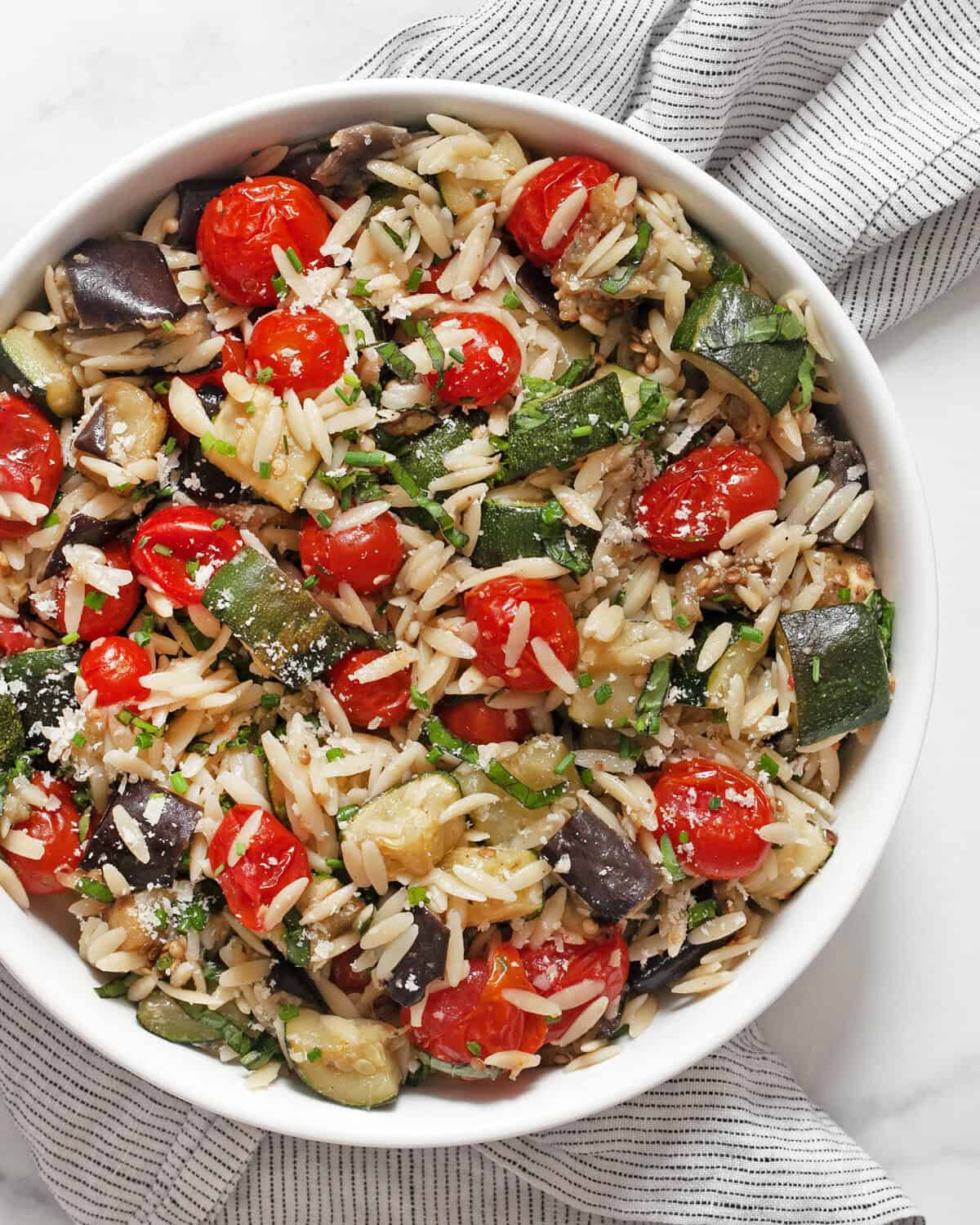 Roasted eggplant, zucchini and tomato orzo in a bowl.