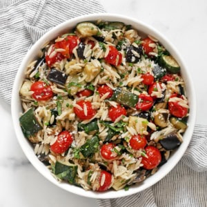 Roasted eggplant, zucchini and tomato orzo in a bowl.