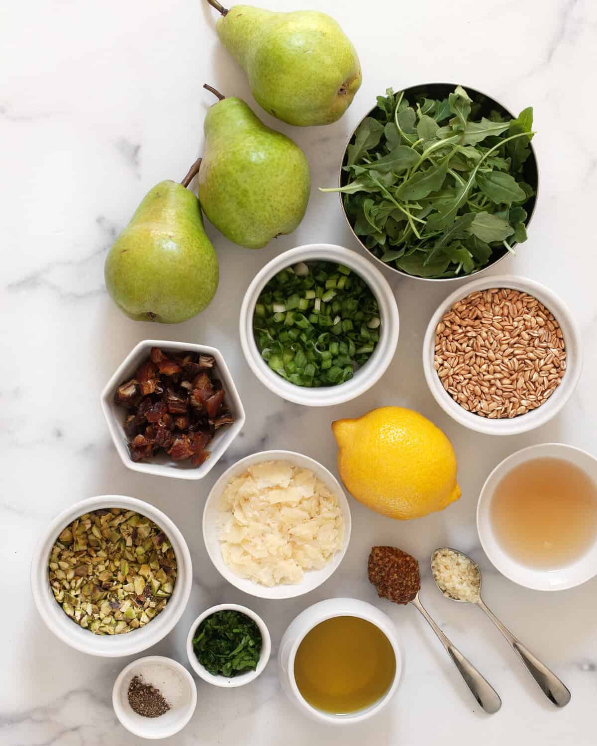 Ingredients including pears, farro, arugula, dates, pistachios, parmesan, lemon, olive oil, garlic, mustard, salt and pepper.