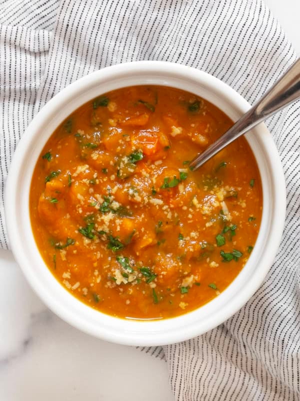 One bowl of creamy pumpkin soup with white beans and kale.