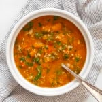 One bowl of creamy pumpkin soup with white beans and kale.