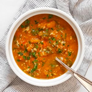 One bowl of creamy pumpkin soup with white beans and kale.