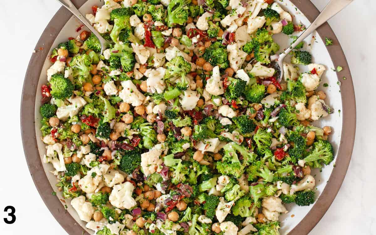 Salad ingredients tossed with dressing in a large bowl.