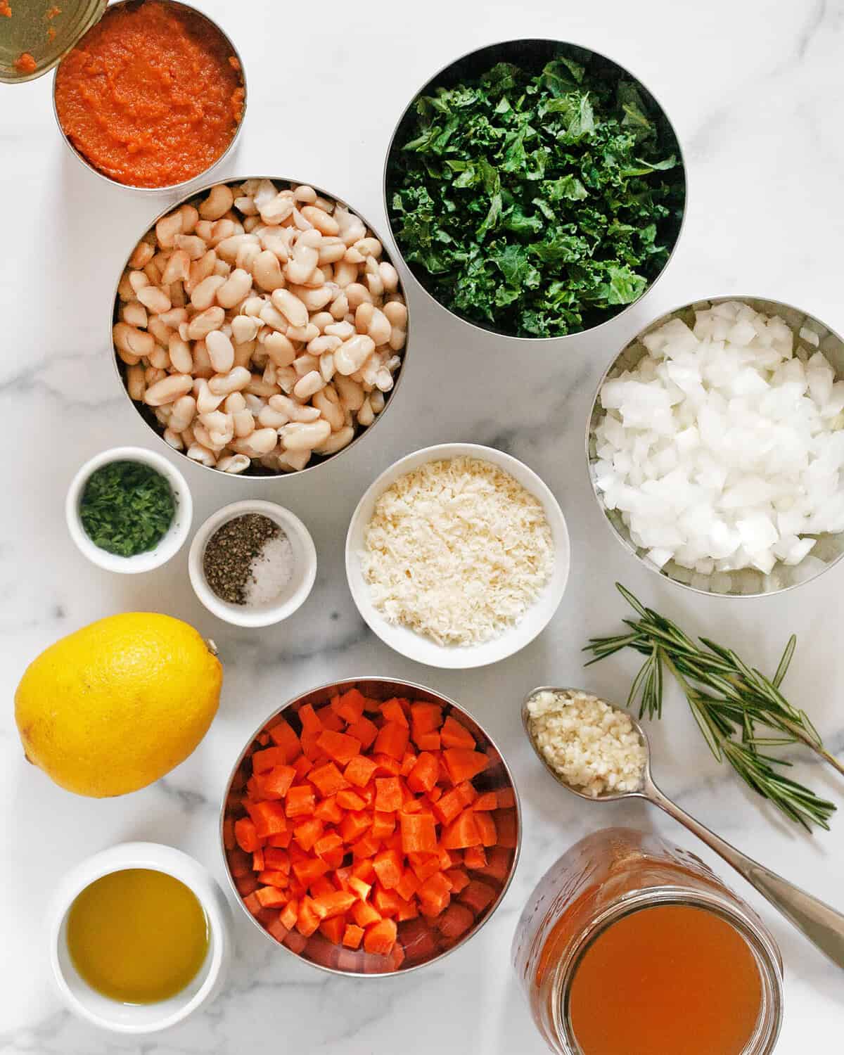 Ingredients including canned pumpkin puree, white beans, kale, onions, parmesan, carrots, lemon, garlic, rosemary, vegetable broth, olive oil, salt, pepper and aprsley