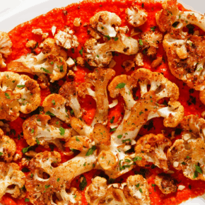 Roasted cauliflower steaks with roasted red pesto on a serving platter.