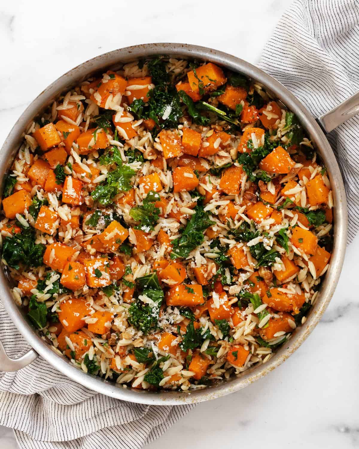 Roasted butternut squash kale orzo in a pan.