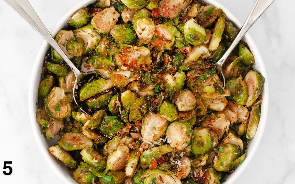 Roasted brussels sprouts stirred with breadcrumbs, parmesan and herbs in a bowl.