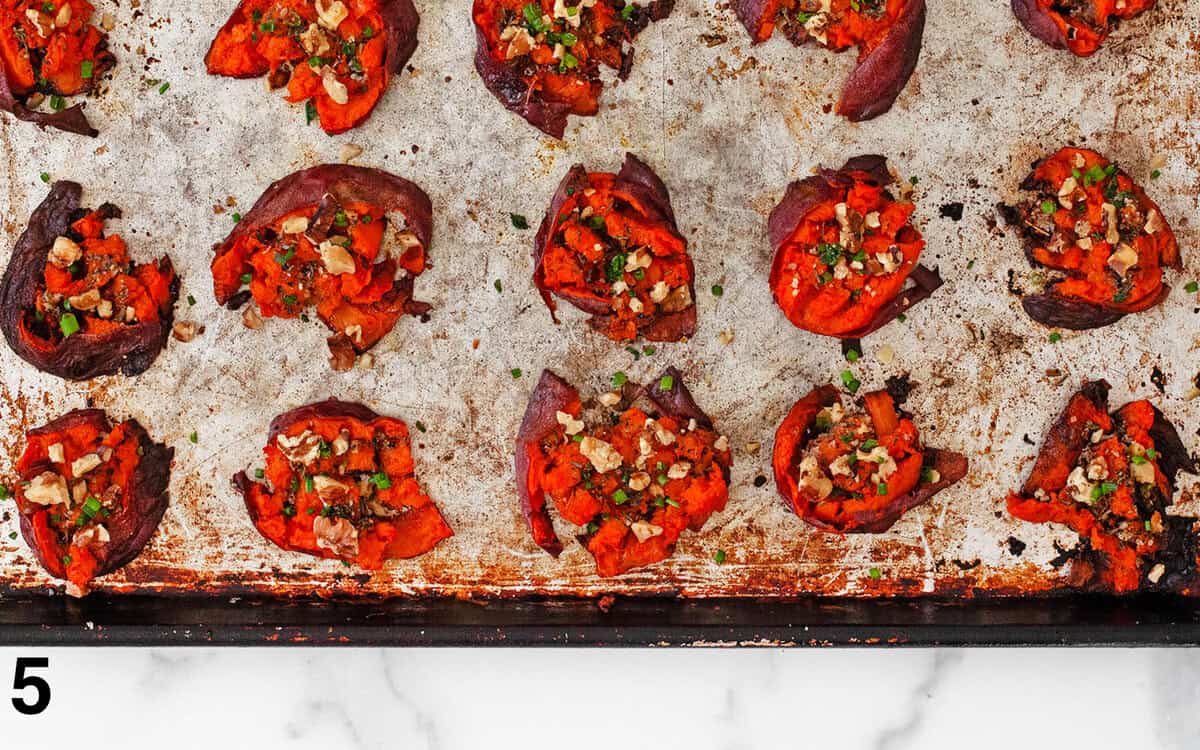 Roasted mashed sweet potatoes on a pan topped with walnuts and chives.