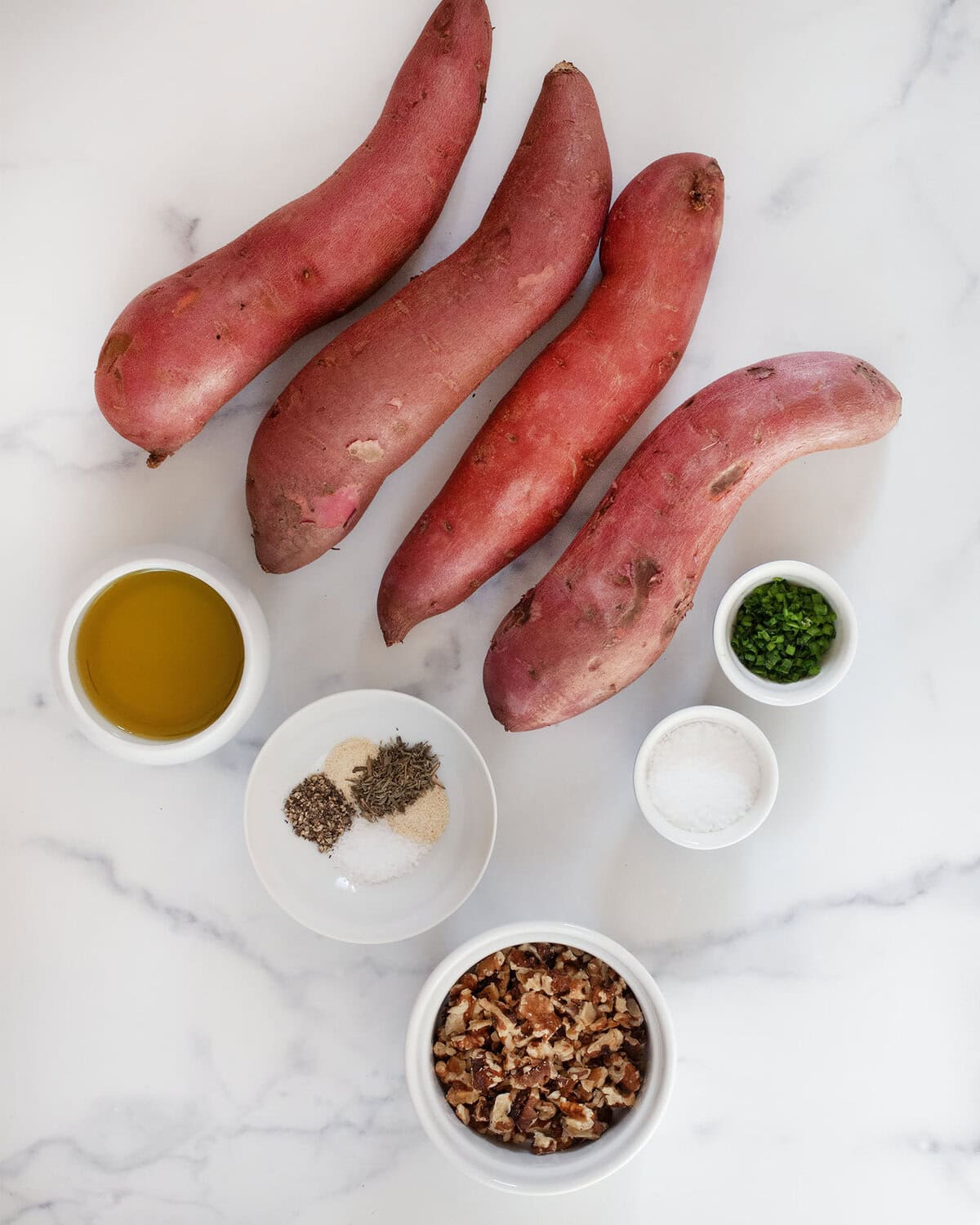 Ingredients including sweet potatoes, olive oil, seasonings, walnuts and chhives.