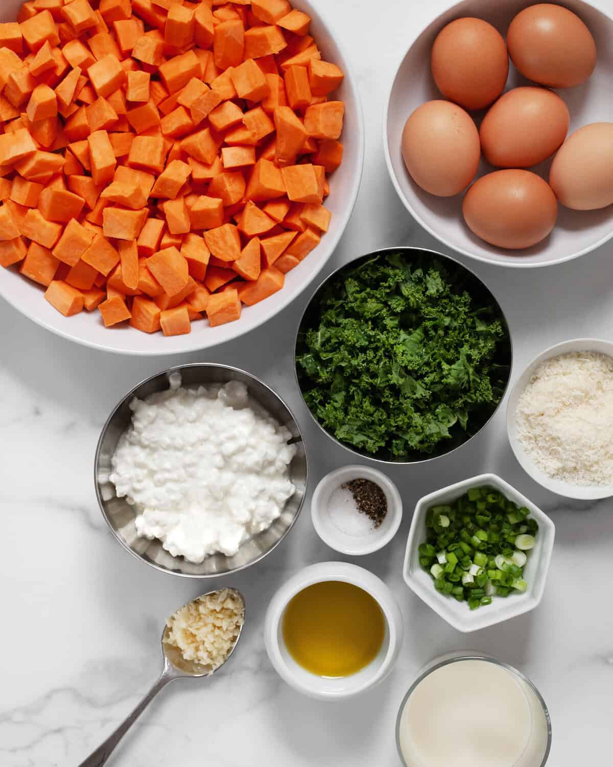 Ingredients including sweet potatoes, kale, parmesan, eggs, milk. cottage cheese, olive oil, scallions, garlic, salt and pepper.