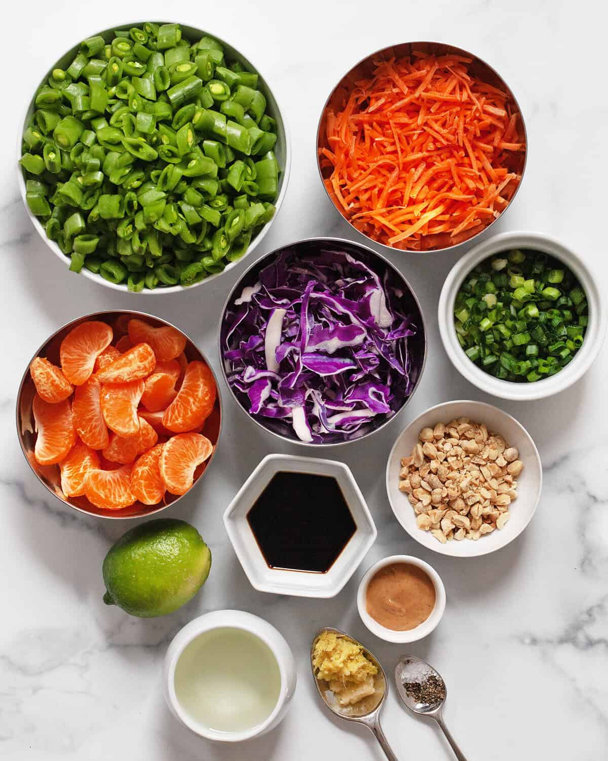 Ingredients including snap peas, mandin oranges, carrots, cabbage, scallions, peanuts, lime, soy sauce, peanut butter, ginger, garlic and oil.