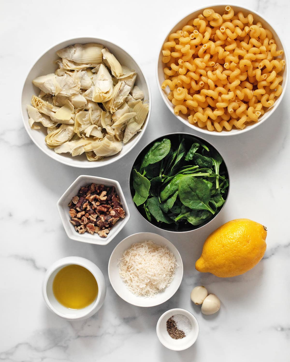 Ingredients including spinach, artichokes, pasta, walnuts, parmesan, lemon, garlic, olive oil, salt and pepper.