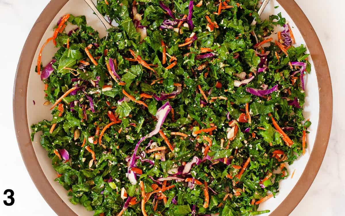 Kale slaw tossed with dressing in a large bowl.