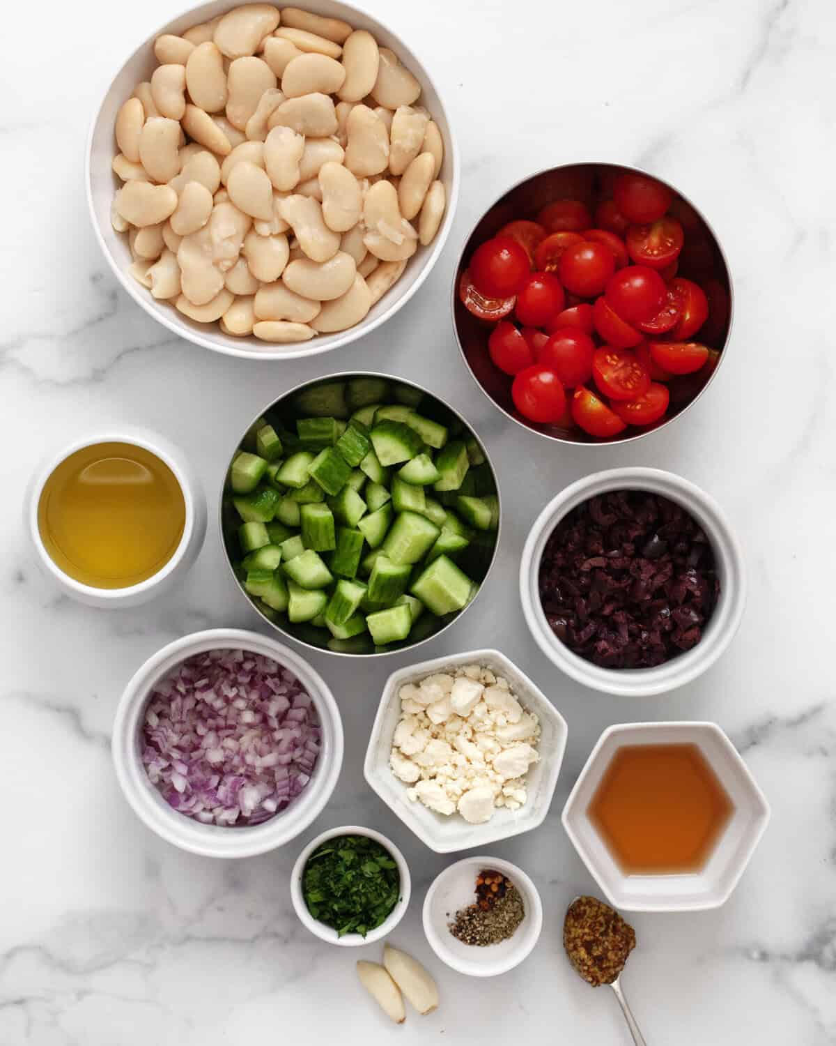Ingredients including butter beans, cherry tomatoes, cucumbers, kalamata olives, red onions, feta, parsley, olive oil, red wine vinegar and seasonings.