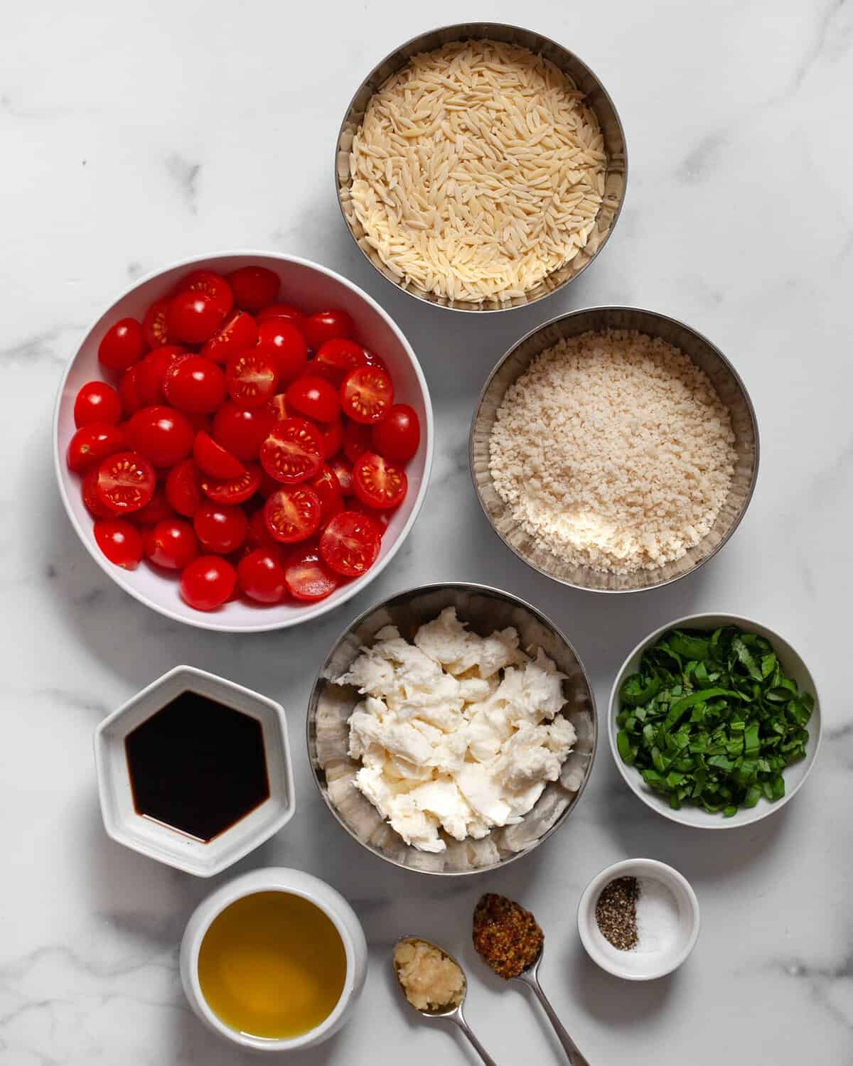 Ingredients including tomatoes, orzo, fresh mozzarella, basil, salt, pepper, balsamic vinegar, olive oil, mustard and garlic.